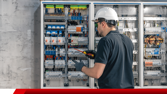 Técnico realizando manutenção em painel elétrico industrial.