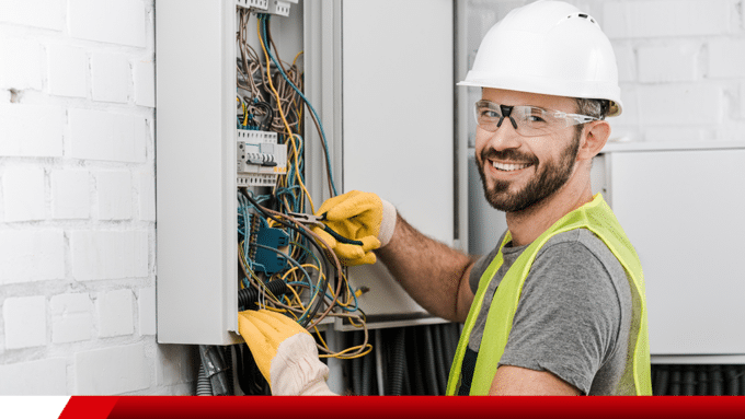 Eletricista trabalhando em quadro de instalação elétrica.