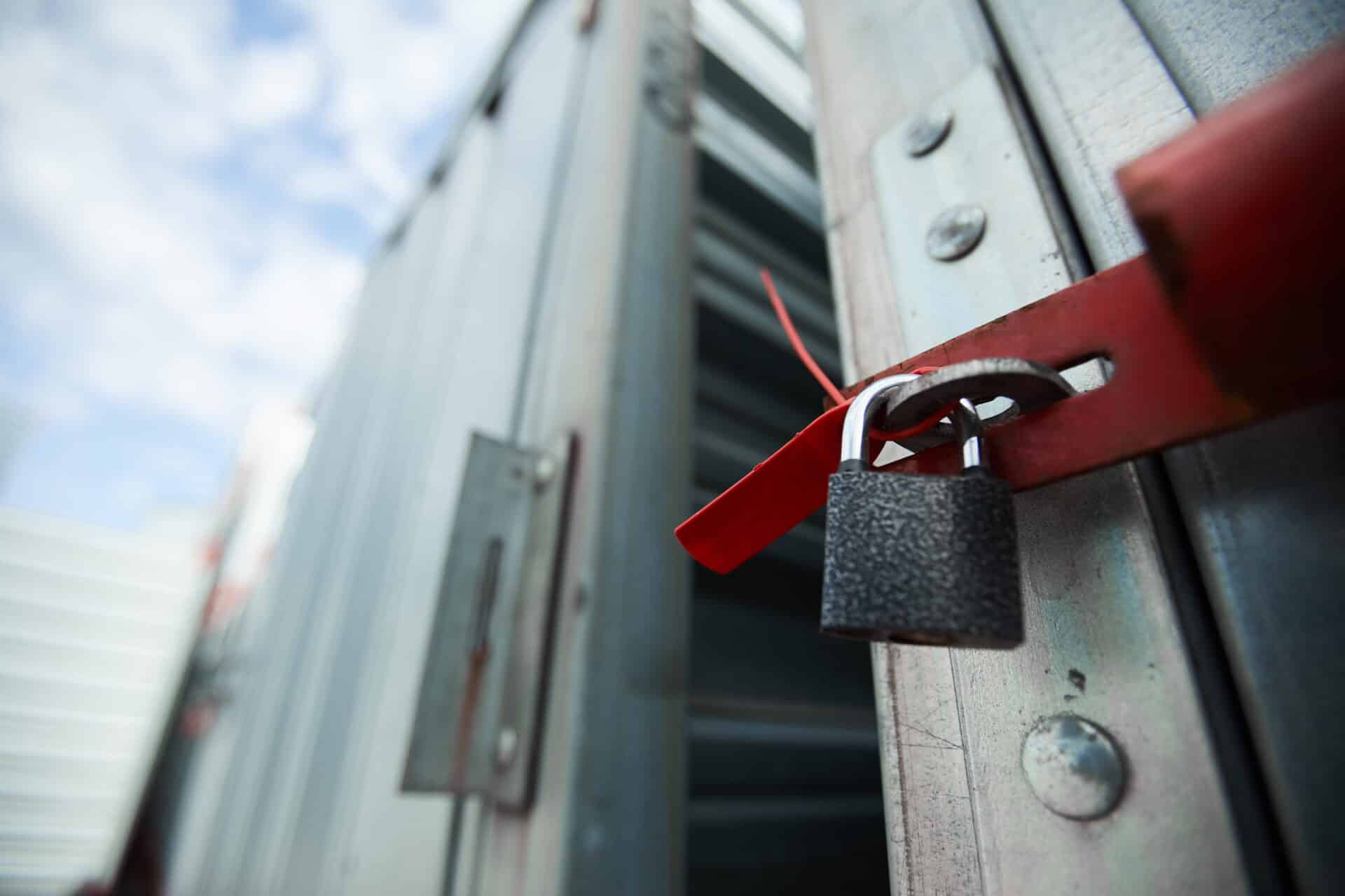 Portão preso por uma fechadura vermelha e um cadiado dourado